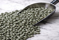 Raw green coffee beans in a metal scoop on a marble surface